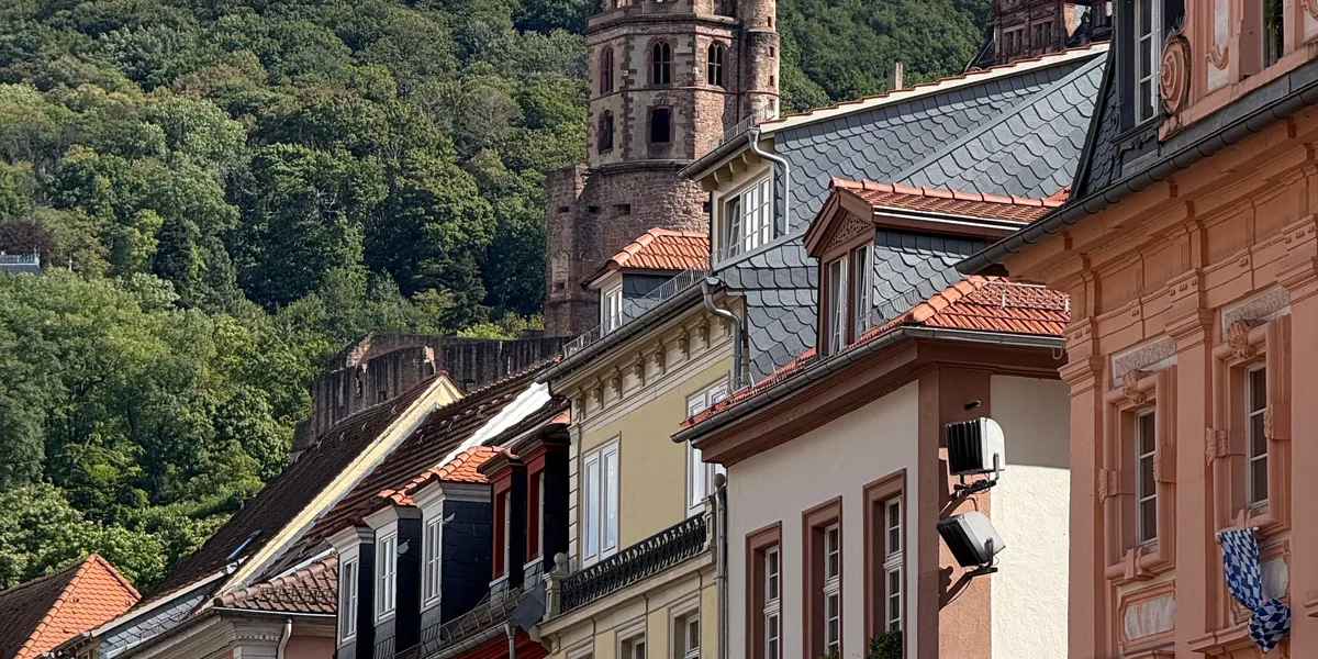 Häuserzeile in der Heidelberger Altstadt, dahinter das Schloss am Hang